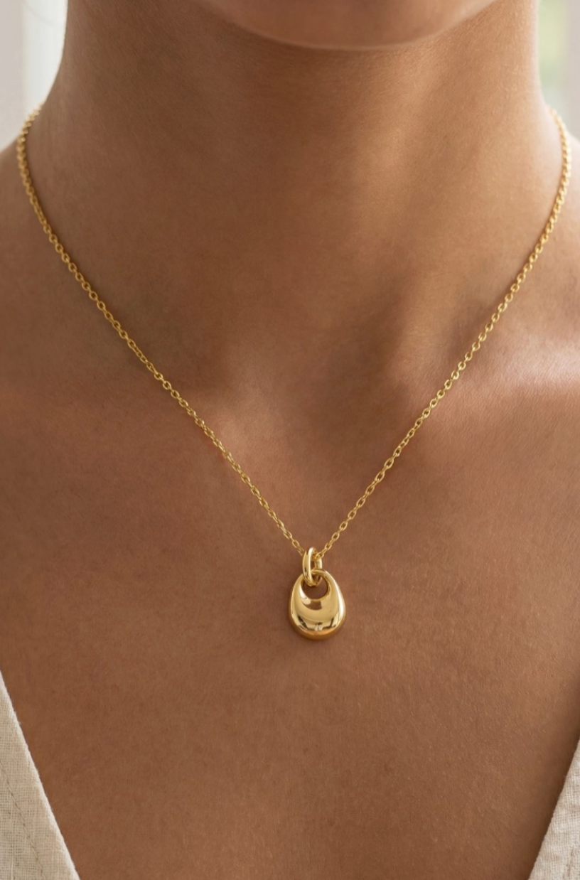 Gold necklace with a small pendant on a person's neck