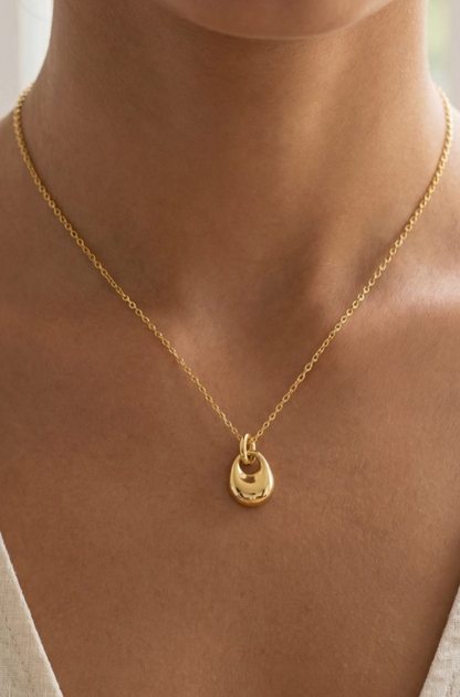 Gold necklace with a small pendant on a person's neck