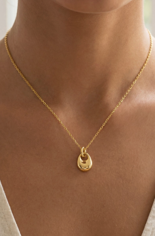 Gold necklace with a small pendant on a person's neck