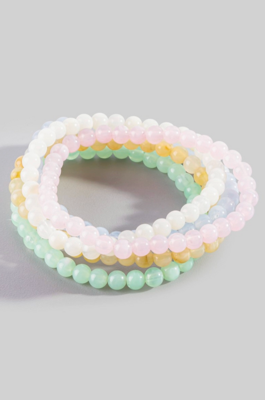 Set of three pastel beaded bracelets on a light gray background