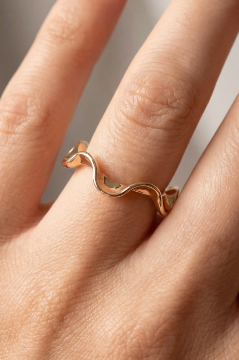 Rose gold ring on a finger against a neutral background