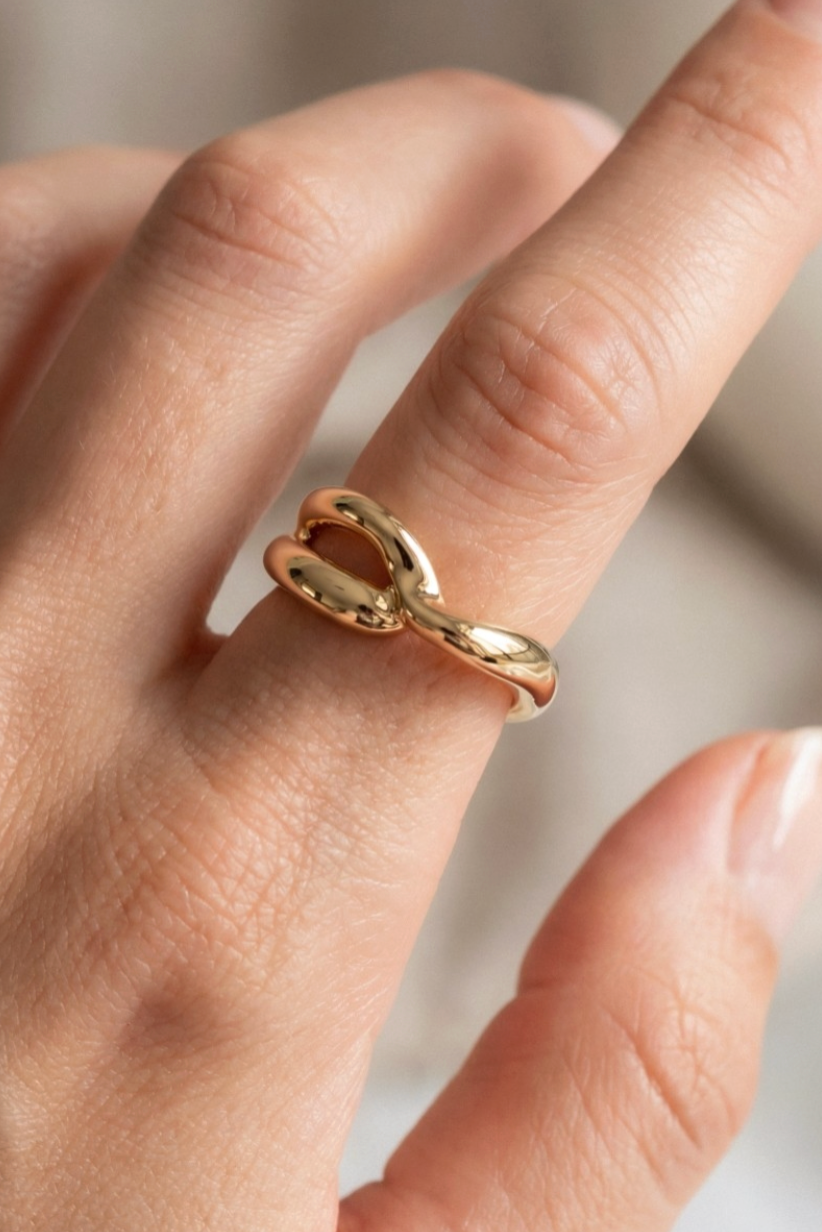 Gold ring on a finger against a neutral background