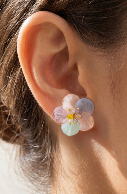 Floral earrings worn on an ear with a neutral background