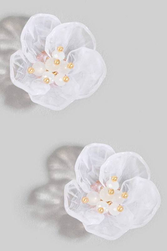 White floral earrings with gold accents on a gray background