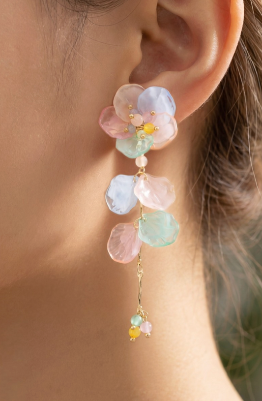 Close-up of a person wearing a floral earring with pastel-colored stones.