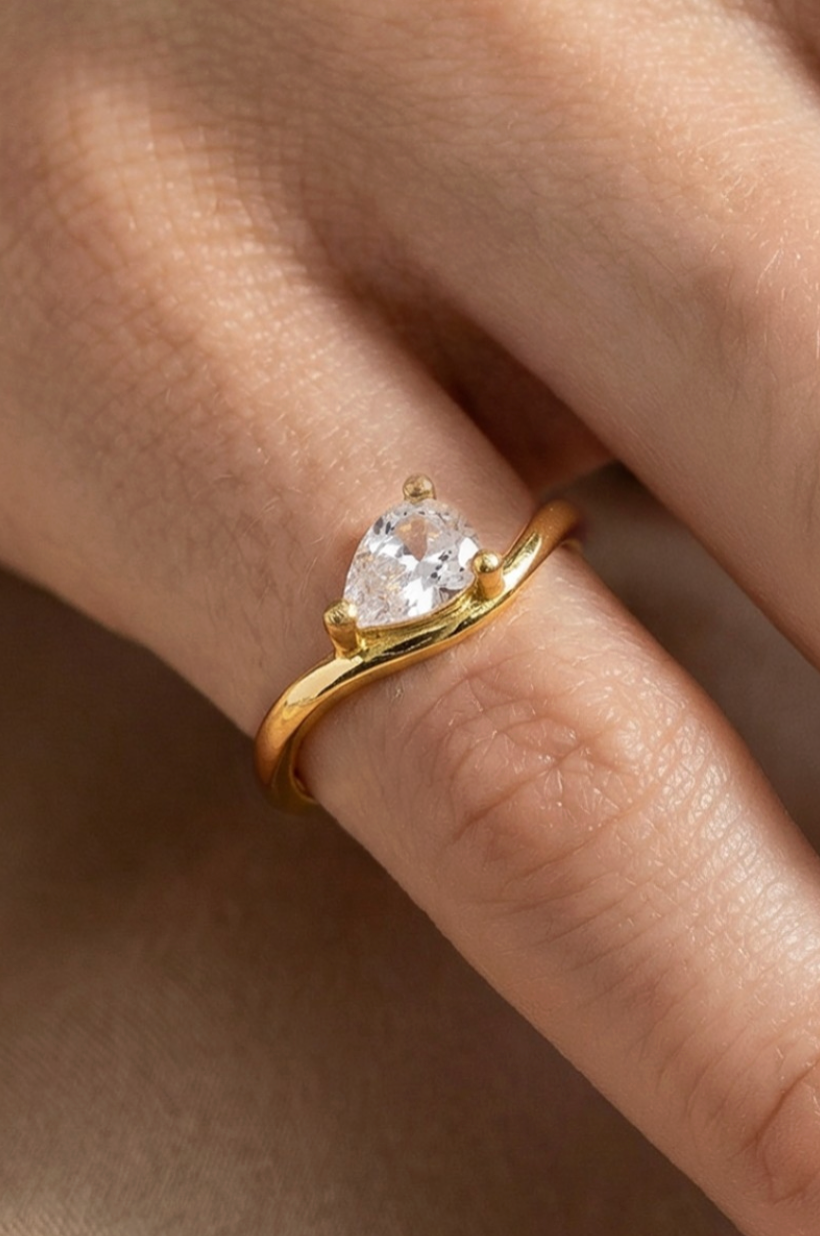 Gold ring with a heart-shaped diamond on a finger