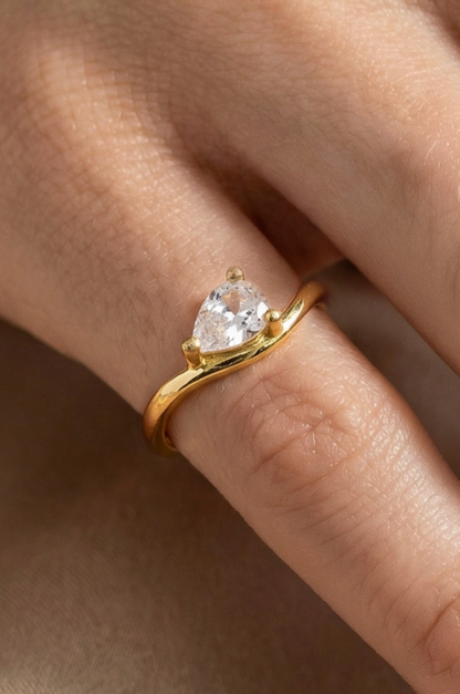 Gold ring with a heart-shaped diamond on a finger