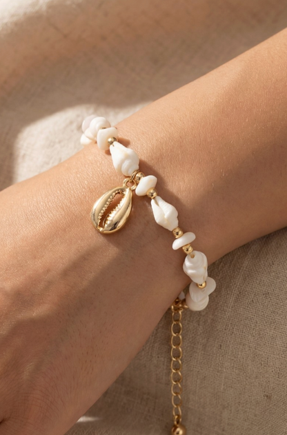 Bracelet with pearls and gold chain on a wrist against a neutral background