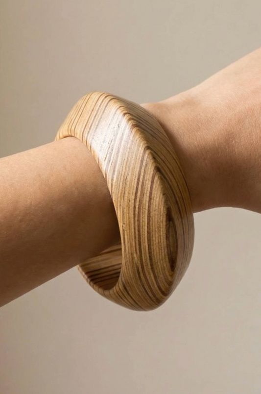 Wooden bangle on a person's wrist against a neutral background