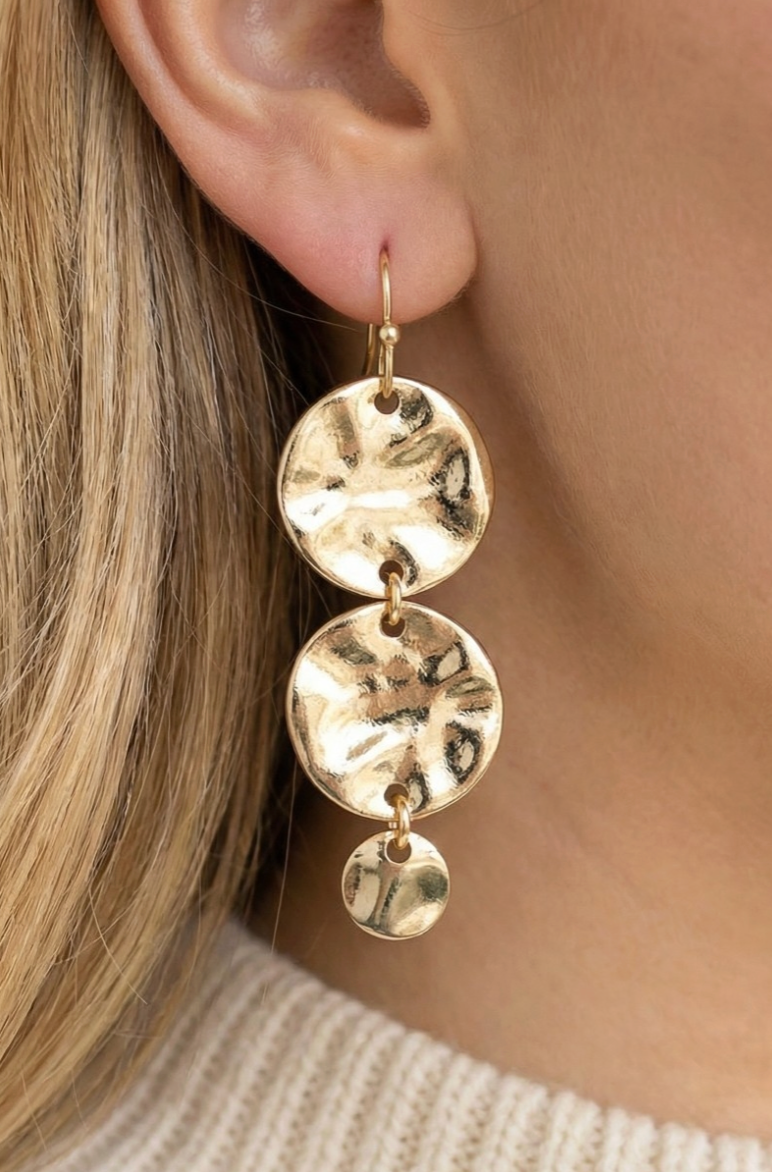 Gold circular earrings worn by a person with blonde hair.