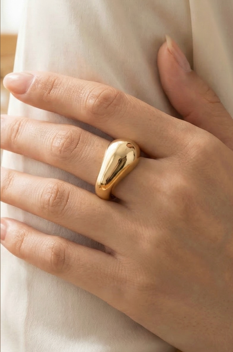 Gold ring on a person's finger with a soft background