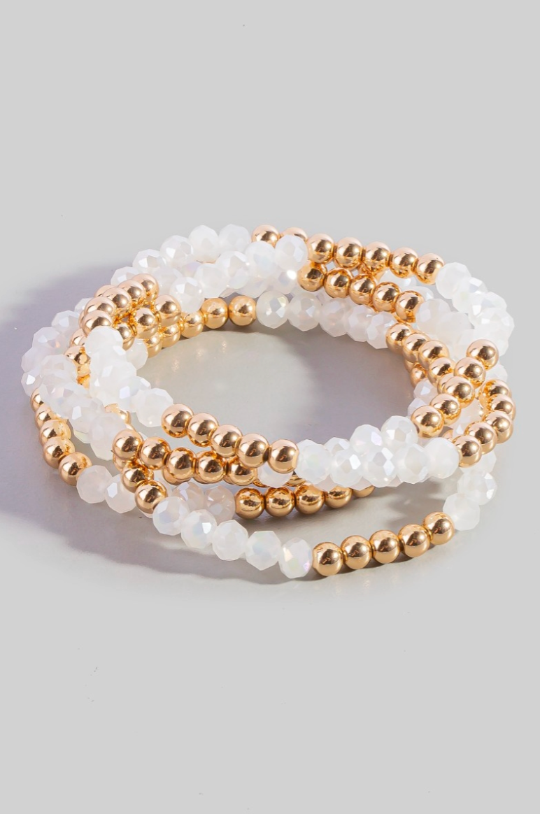 Set of white and gold beaded bracelets on a light gray background