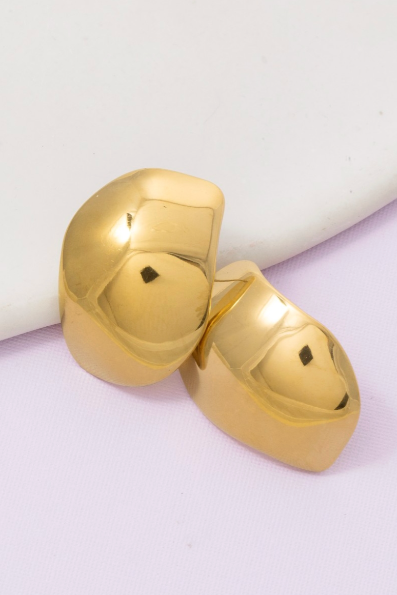 Gold heart-shaped earrings on a light purple background