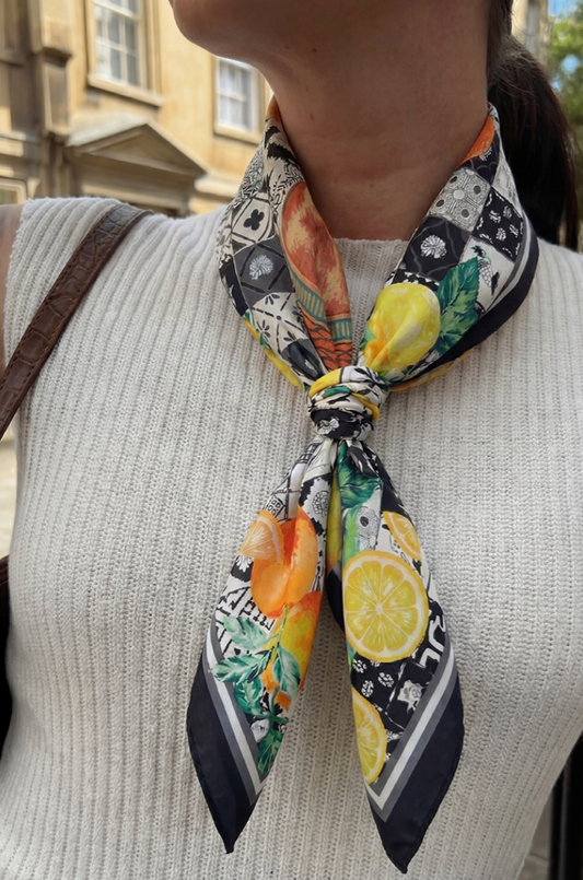 Person wearing a colorful scarf with fruit pattern in an urban setting