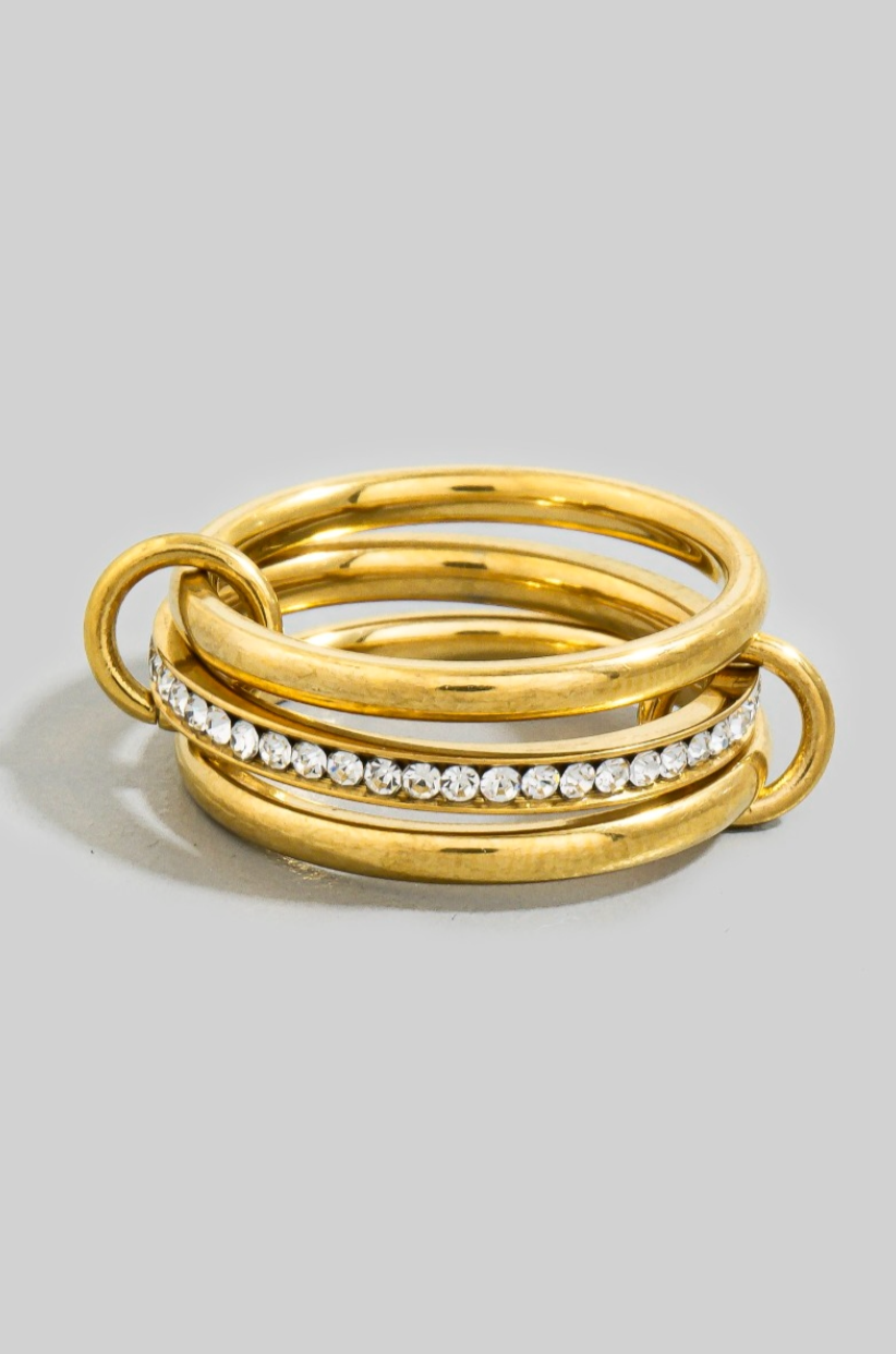 Stack of gold rings with embedded diamonds on a light gray background