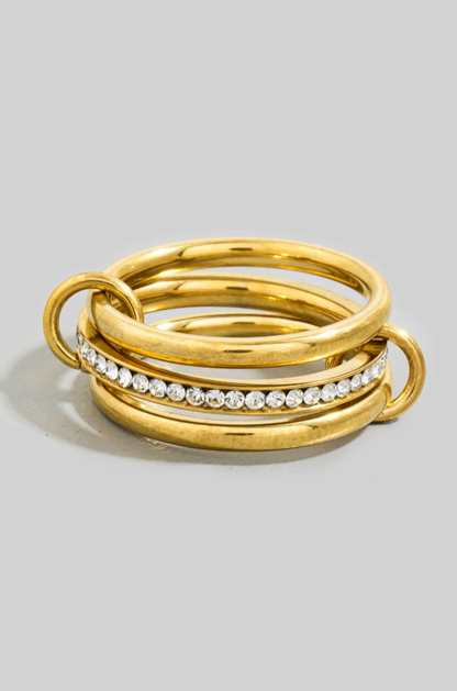 Stack of gold rings with embedded diamonds on a light gray background