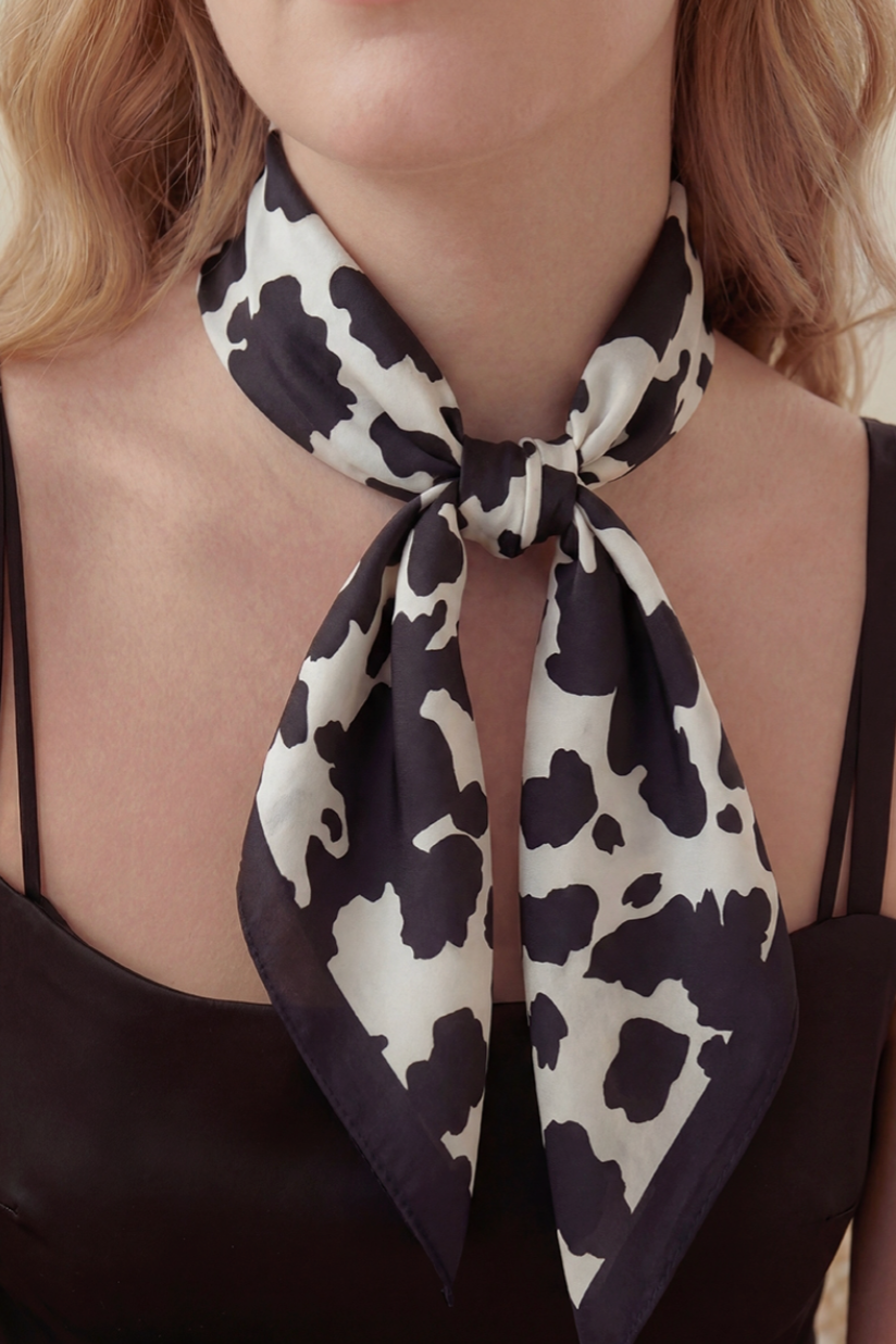 Person wearing a black and white cow patterned scarf around their neck