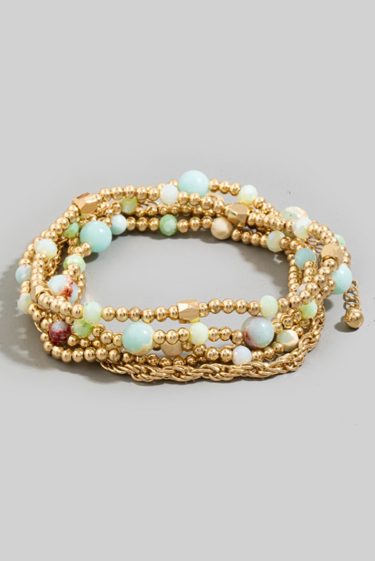 Multistrand beaded bracelet with gold accents on a gray background