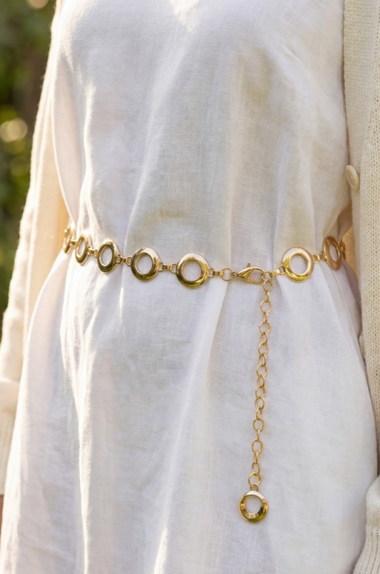Gold chain belt on a white garment with a blurred natural background