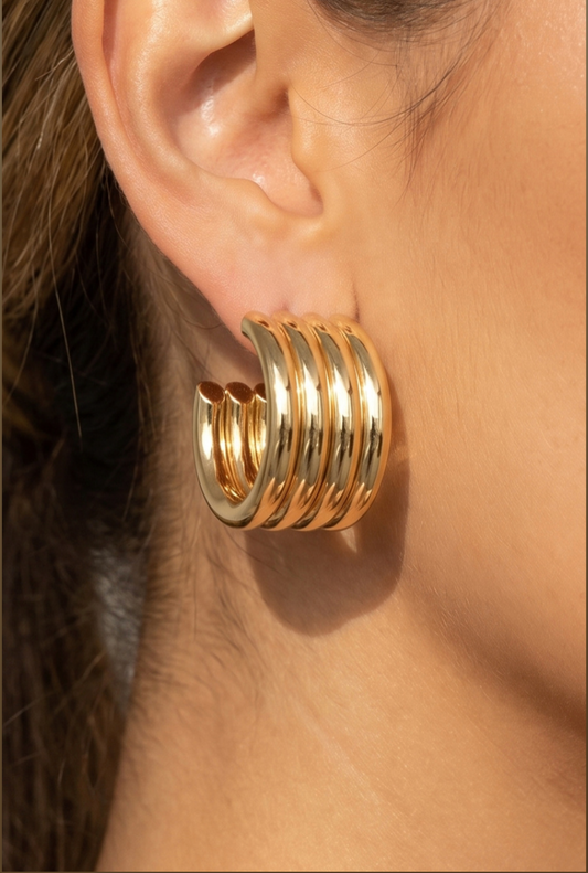 Gold ribbed chunky hoop earrings featuring multiple polished parallel tube bands with a sculptural stacked-hoop design.