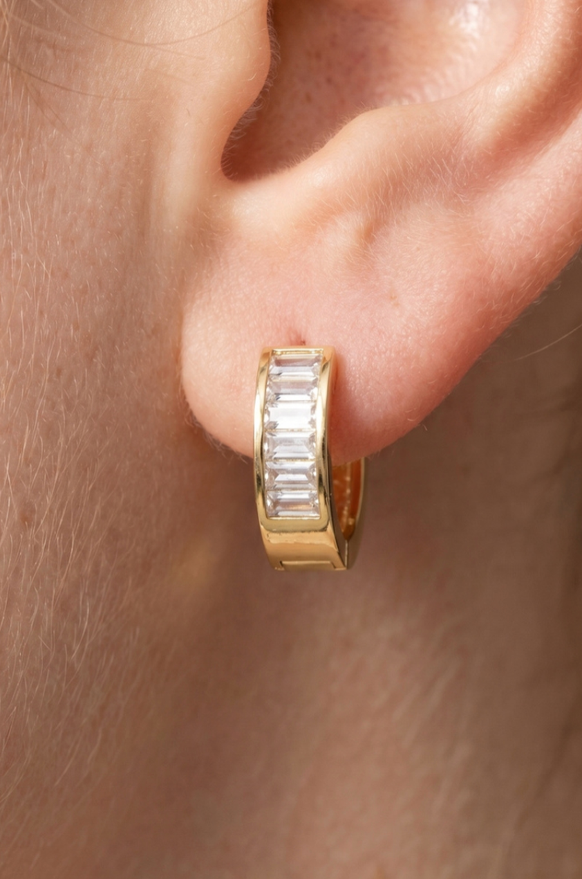 Gold huggie earrings featuring channel-set baguette cubic zirconia stones with a polished finish.
