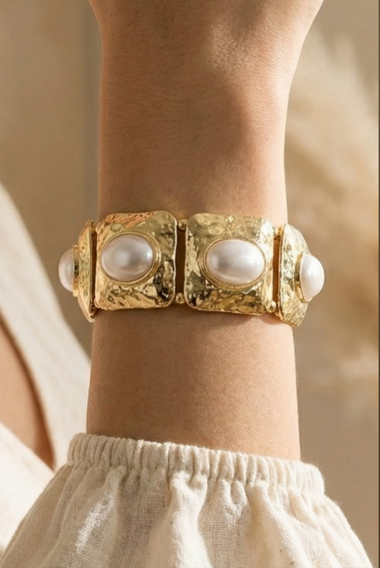 Gold stretch bracelet featuring hammered square links with oval faux pearl accents.