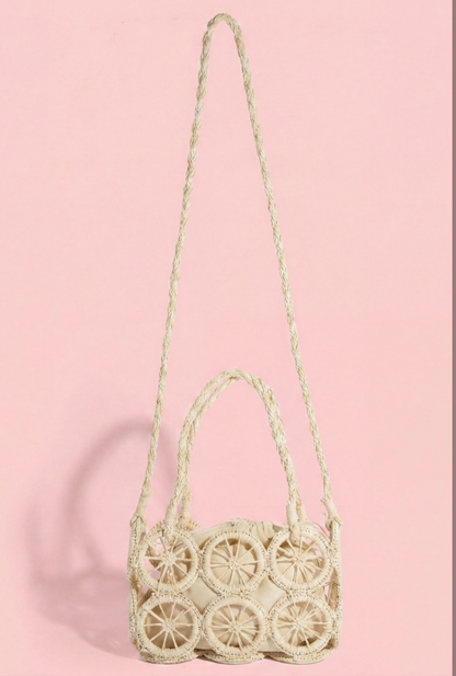 Woven rattan-style crossbody bag with decorative open-work medallion panels and an adjustable braided strap.