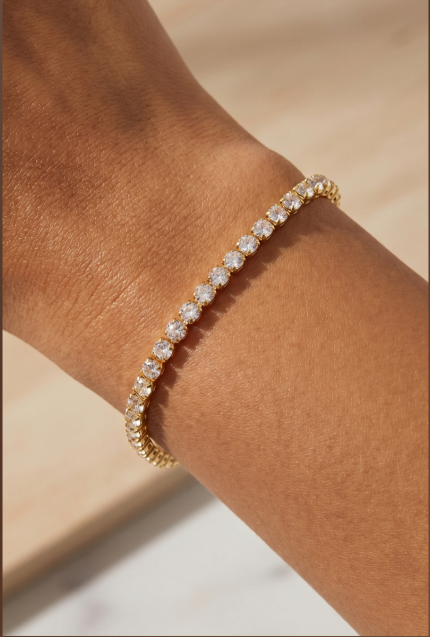 Gold-tone tennis bracelet featuring a continuous row of sparkling prong-set cubic zirconia stones with a secure box clasp.