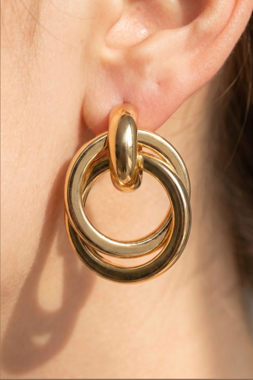Gold-dipped interlocking doorknocker earrings with polished circular rings and oval stud posts.