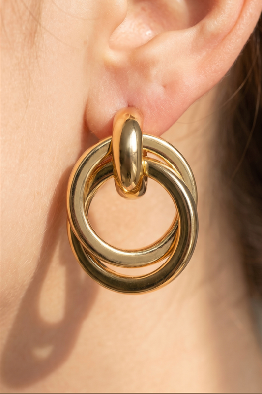Gold-dipped interlocking doorknocker earrings with polished circular rings and oval stud posts.