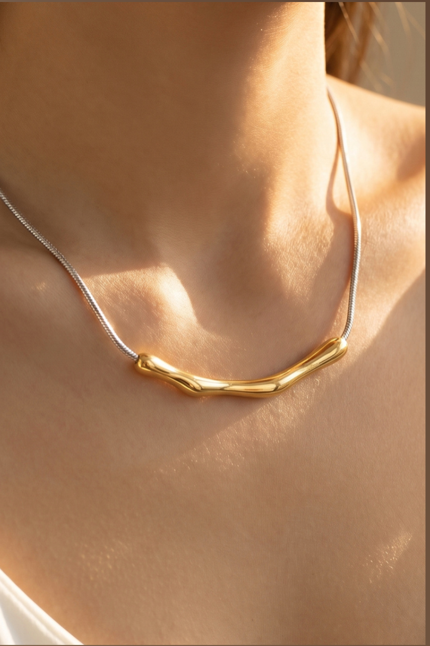 Gold organic bar pendant necklace on a herringbone chain worn on a model.
