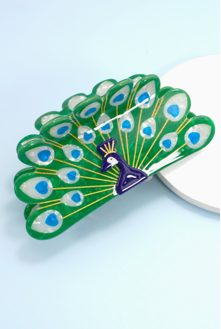 Green peacock-shaped claw hair clip with blue feather details and gold accents.