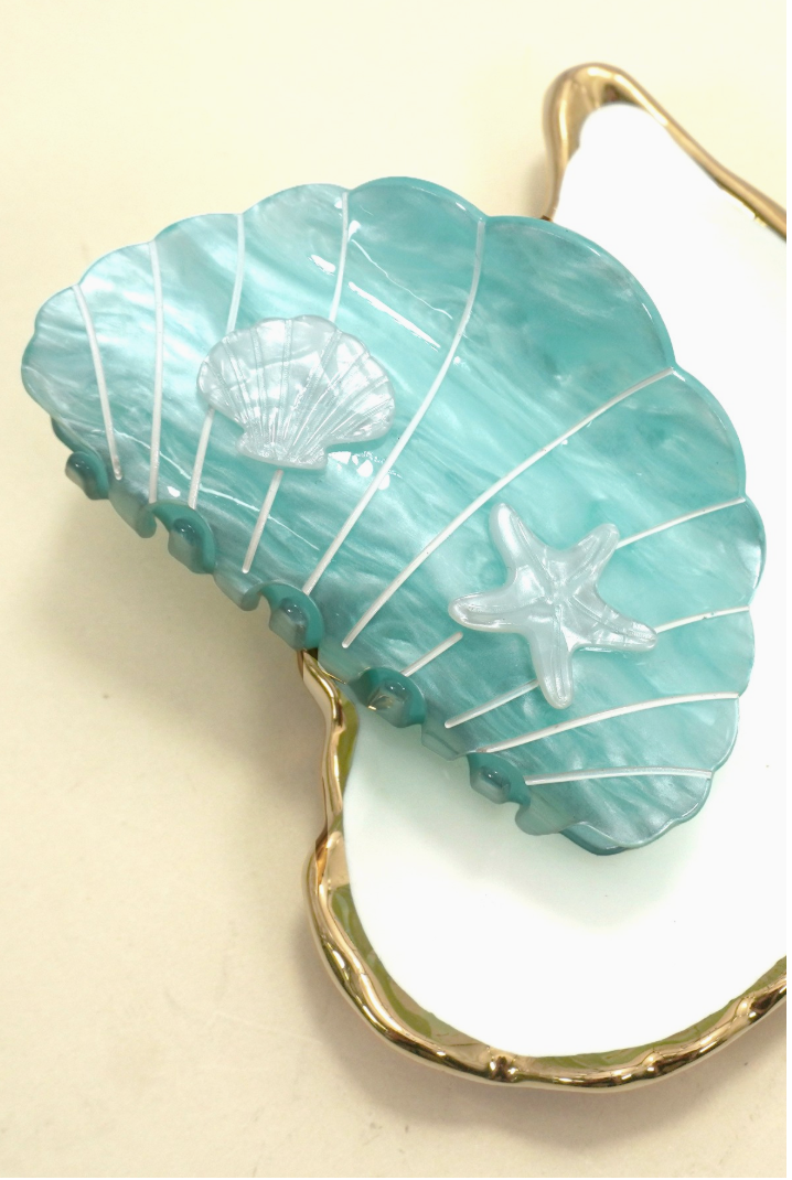 Marbled sky blue seashell-shaped hair claw clip with white shell and starfish details.