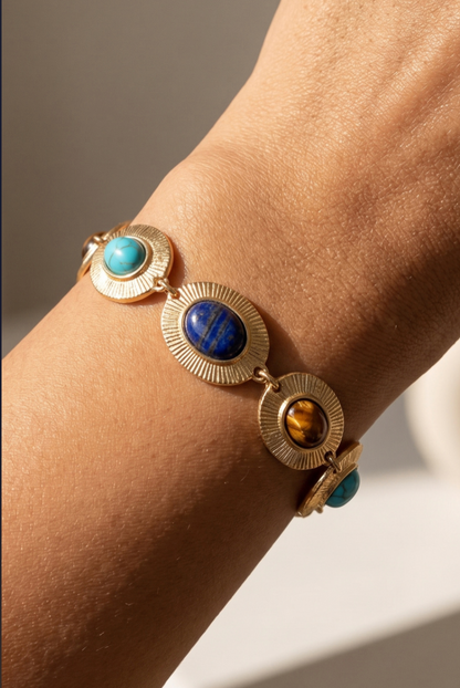 Gold oval link bracelet with engraved sunburst details and multicolored acrylic dome accents.