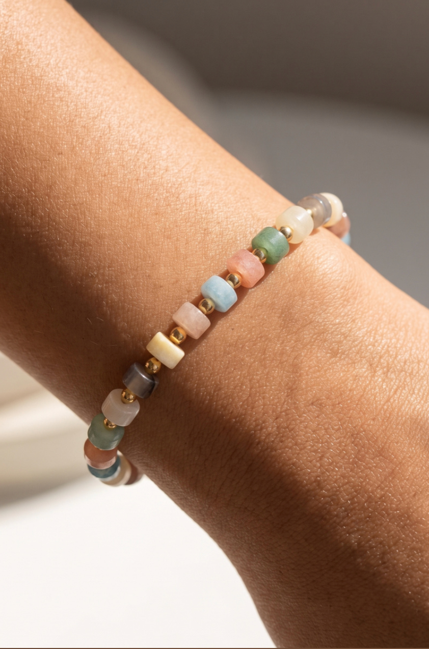 Stretch bracelet featuring light multi-color semi-precious stone beads with gold spacer beads.
