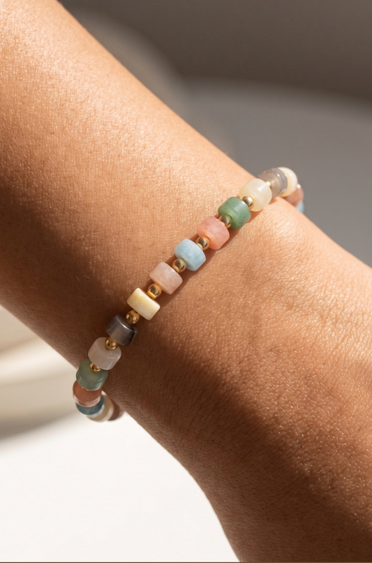 Stretch bracelet featuring light multi-color semi-precious stone beads with gold spacer beads.
