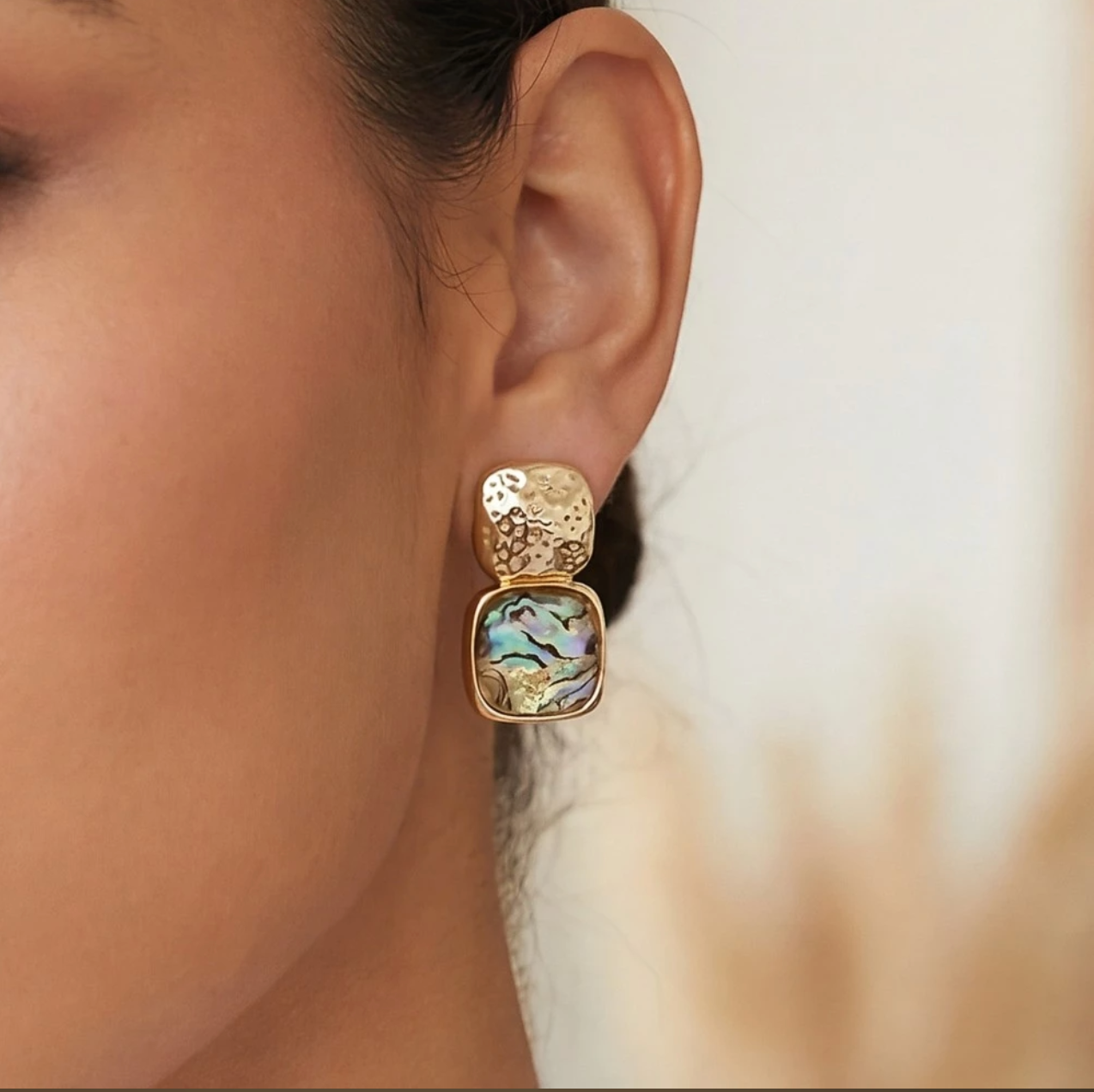 Gold textured drop earrings with iridescent blue faceted resin stones in a bezel setting.