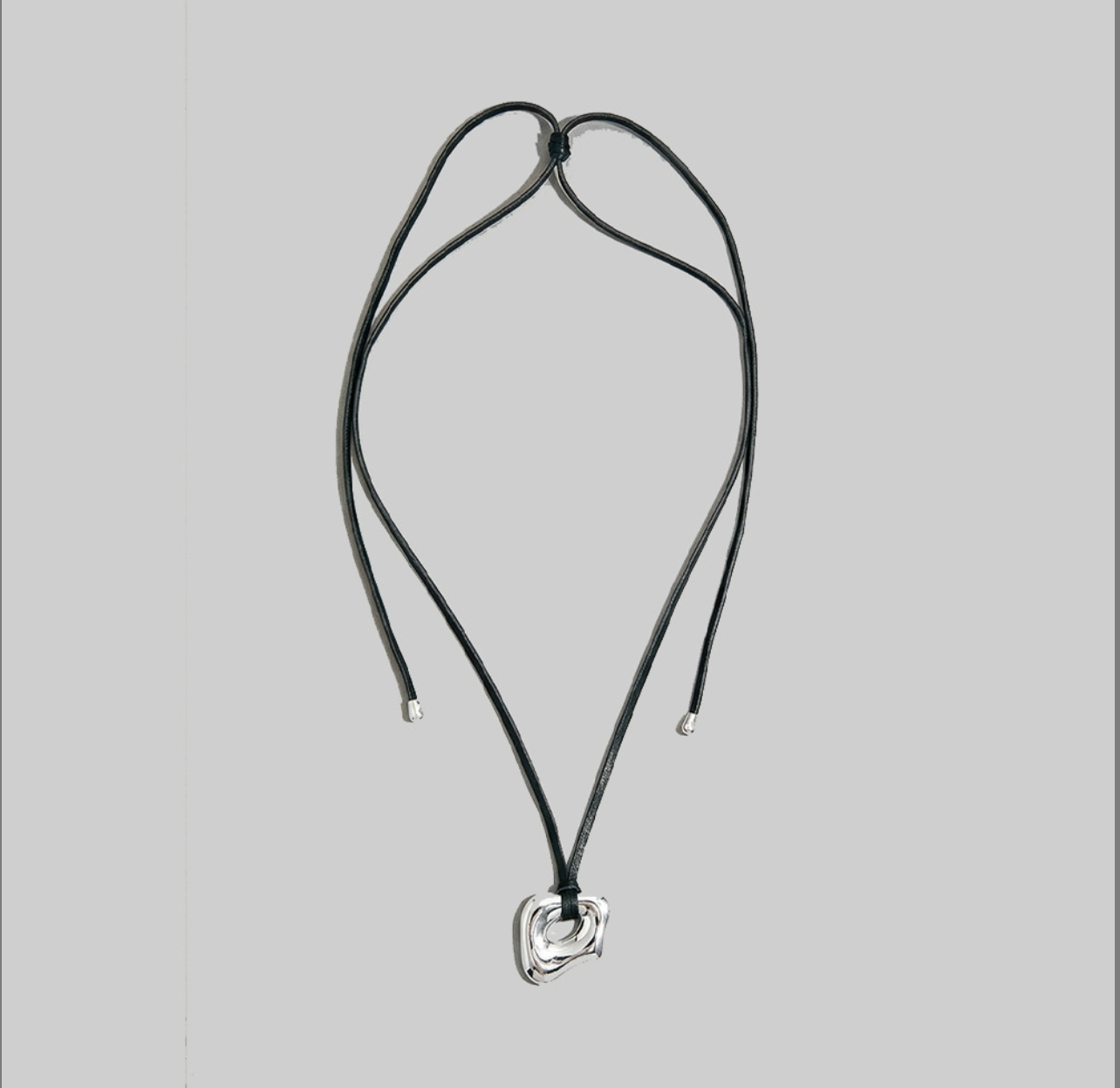 Black genuine leather adjustable cord necklace with a sculptural abstract silver pendant.
