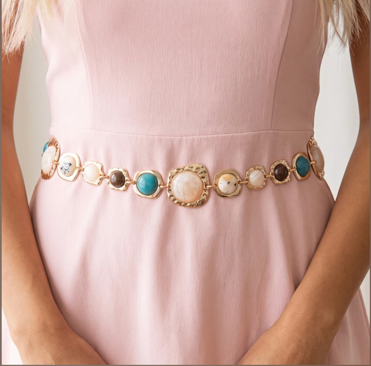 Hammered gold-tone chain belt with mixed cabochon stone accents and adjustable extender chain worn over a blush pink dress.