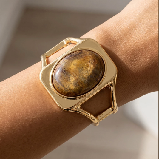 Gold-tone geometric cuff bracelet with a marbled brown oval cabochon stone centerpiece.