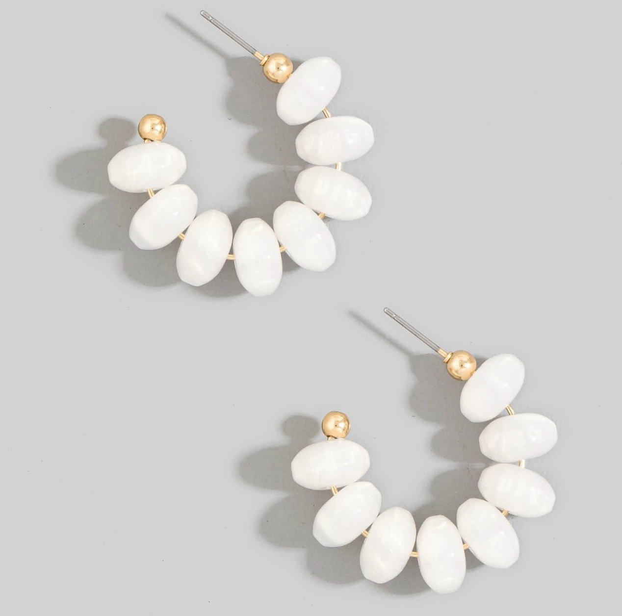 White chunky oval resin beaded hoop earrings with small gold-tone accents and post-back closures.
