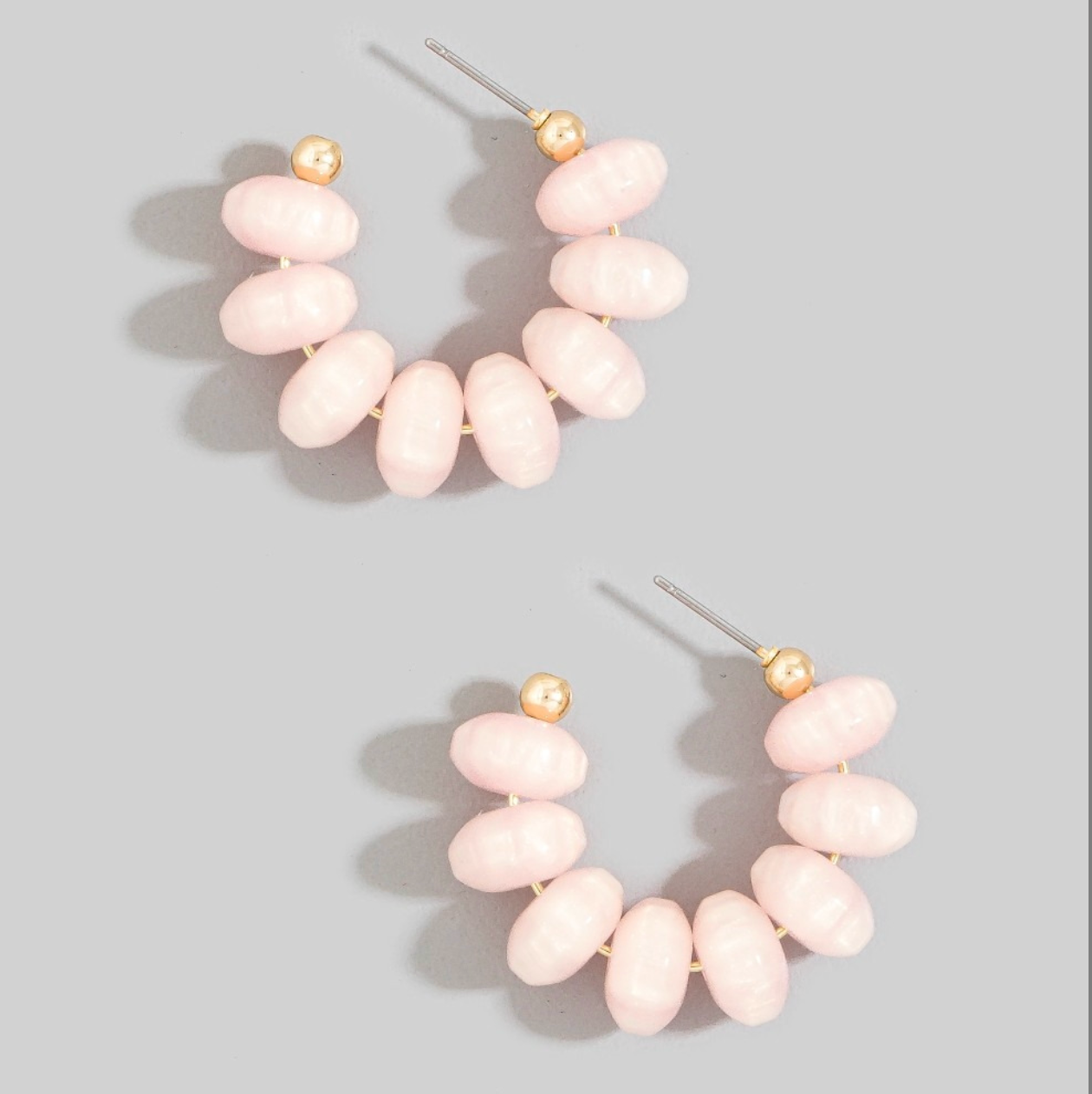 Light pink chunky oval resin beaded hoop earrings with small gold-tone accents and post-back closures.