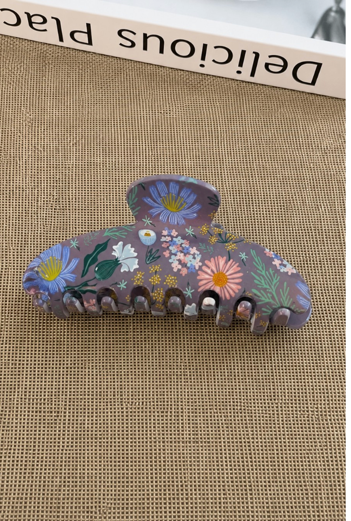 The Garden Room oversized acrylic hair claw clip with colorful botanical floral print on a muted purple background.
