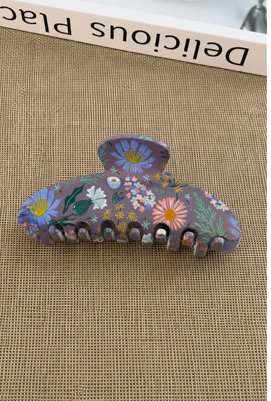The Garden Room oversized acrylic hair claw clip with colorful botanical floral print on a muted purple background.