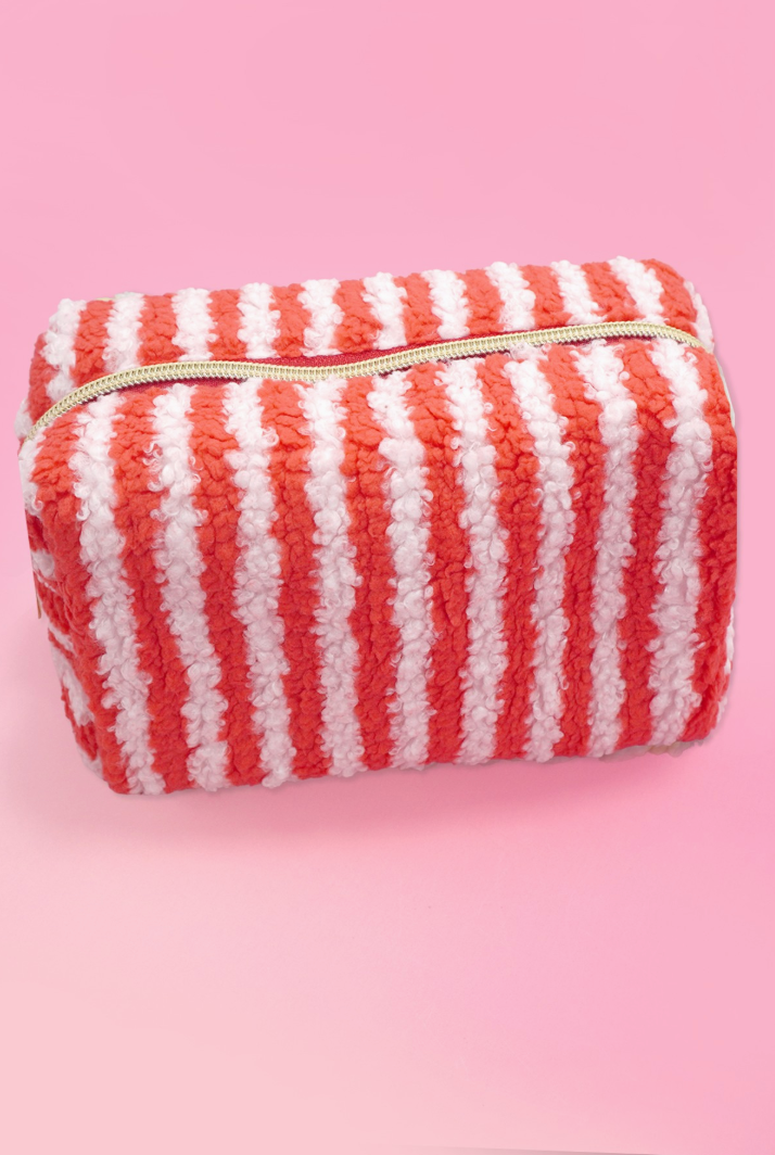 Red and white striped sherpa makeup pouch with gold zipper and soft teddy fleece texture.