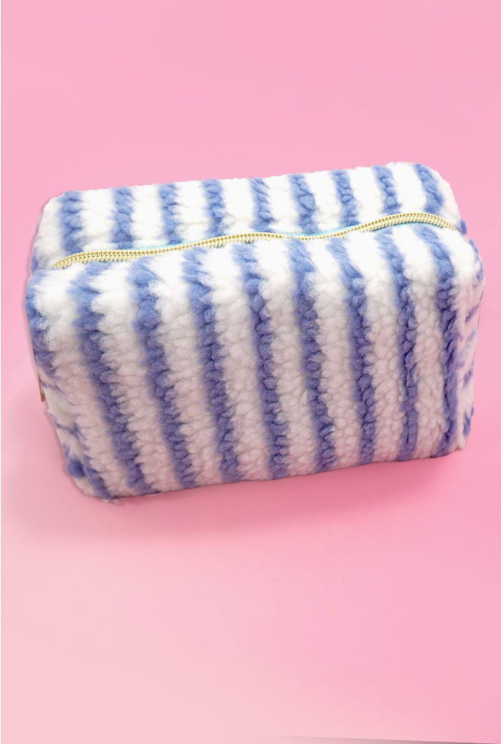 Blue and white striped sherpa cosmetic pouch with gold zipper and plush teddy fabric.