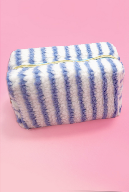 Blue and white striped sherpa cosmetic pouch with gold zipper and plush teddy fabric.