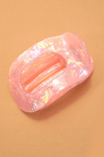 Pink iridescent claw clip on a beige background