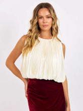 Load image into Gallery viewer, Woman wearing an ivory pleated sleeveless blouse with a bubble hemline paired with a red velvet skirt.