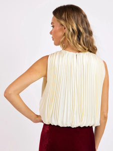 Woman wearing a white pleated top and red skirt on a white background
